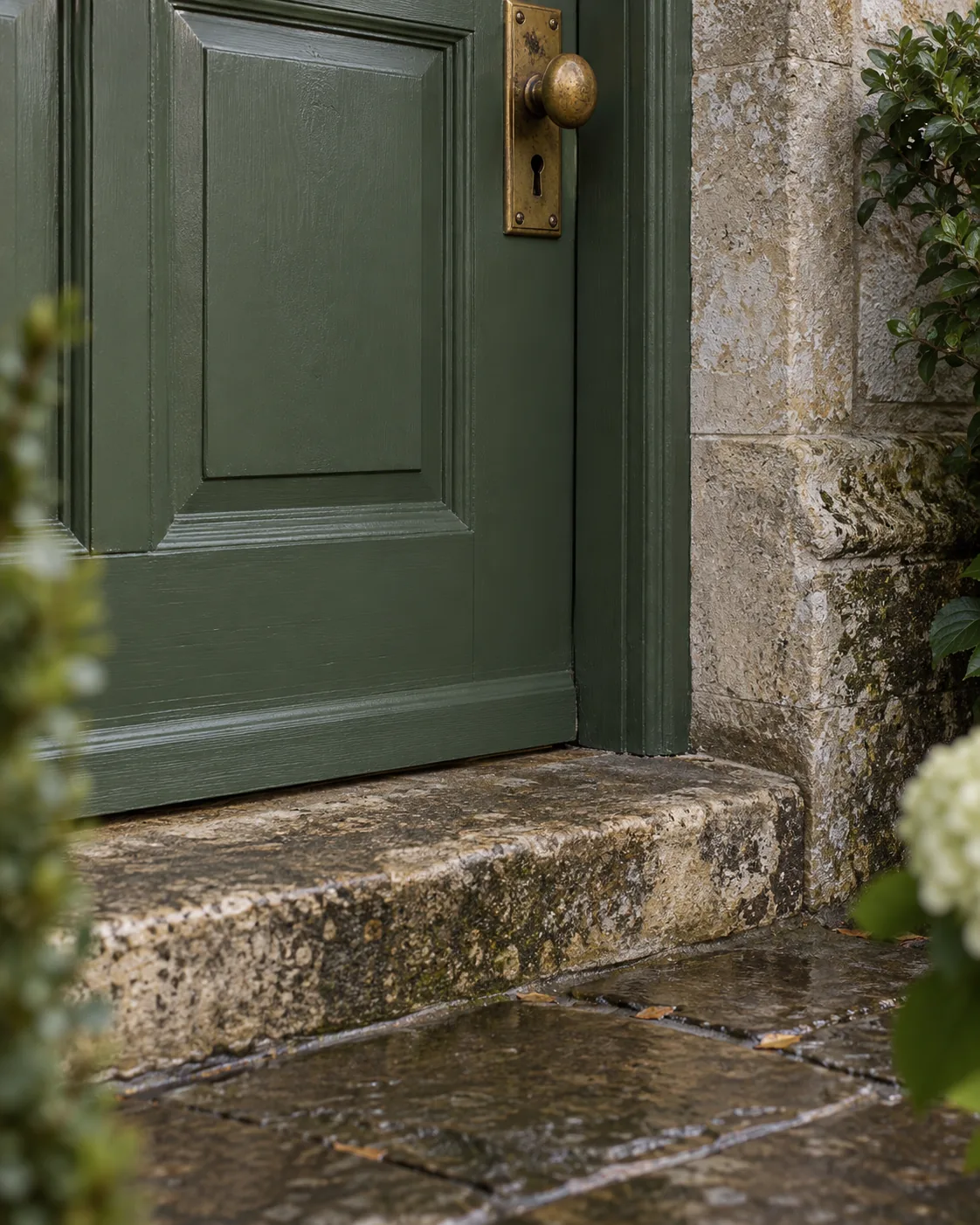 Green painted timber door meeting a weathered stone threshold